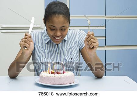 Stock Photo - A young woman about to eat a birthday cake. Fotosearch