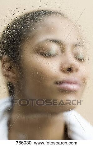 Stock Image - A young woman behind steamed glass. Fotosearch