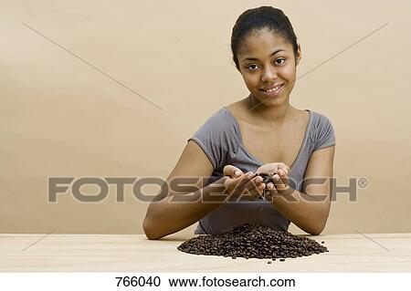 Stock Image - A young woman holding coffee beans. Fotosearch