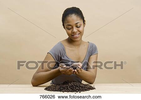 A young woman holding coffee beans View Large Photo Image Stock Photograph - A young woman holding coffee beans. Fotosearch