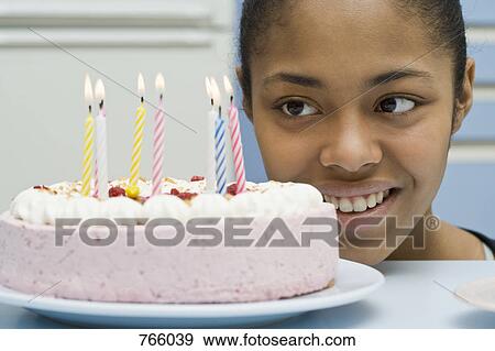 A young woman looking at a birthday cake View Large Photo Image Stock Photo - A young woman looking at a birthday cake. Fotosearch