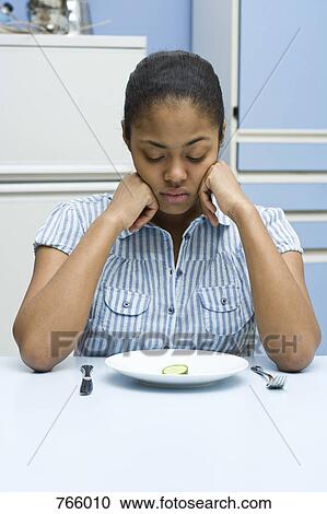 A young woman looking down at a slice of cucumber on a plate View Large Photo Image Stock Image - A young woman looking down at a slice of cucumber on a plate. Fotosearch