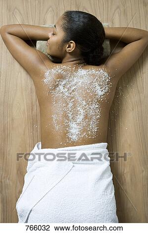 Stock Image - A young woman lying on her front and having a spa treatment. Fotosearch