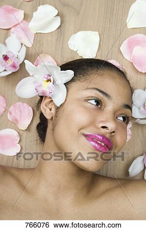 Stock Photograph - A young woman lying surrounded by flowers. Fotosearch
