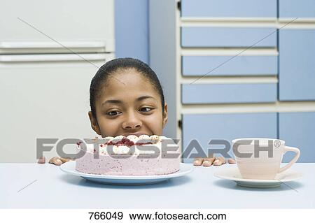 Stock Photo - A young woman peeking at a cake. Fotosearch