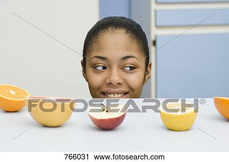 A young woman peeking over a counter at fruit View Large Photo Image Stock Image - A young woman peeking over a counter at fruit. Fotosearch