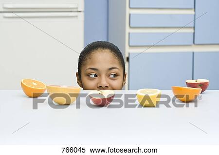 A young woman peeking over a counter with fruit on it View Large Photo Image Stock Photography - A young woman peeking over a counter with fruit on it. Fotosearch