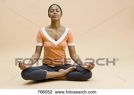 A young woman sitting in the lotus position View Large Photo Image Stock Image - A young woman sitting in the lotus position. Fotosearch