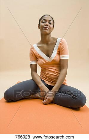 A young woman sitting on an exercise matt View Large Photo Image Stock Photo - A young woman sitting on an exercise matt. Fotosearch