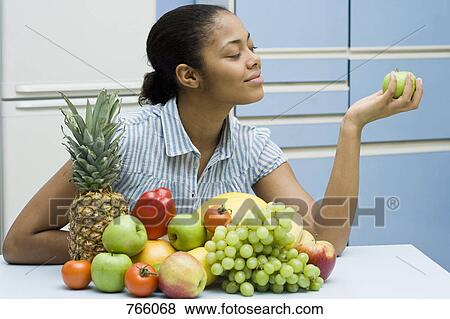 Stock Photo - A young woman sitting with fruit. Fotosearch