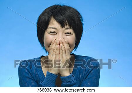 Stock Image - Portrait of a woman laughing and covering her face. Fotosearch