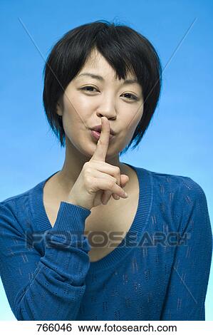Stock Photograph - Portrait of a woman with her finger on her lips. Fotosearch