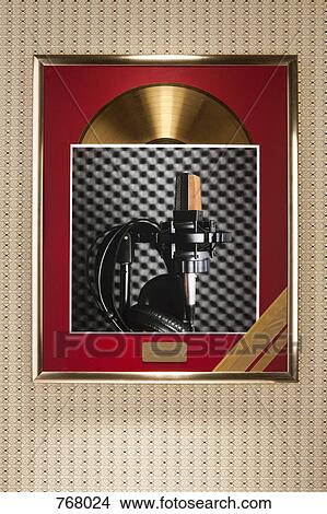 A photograph of a microphone and headphones on top of a framed gold record View Large Photo Image Picture - A photograph of a microphone and headphones on top of a framed gold record. Fotosearch