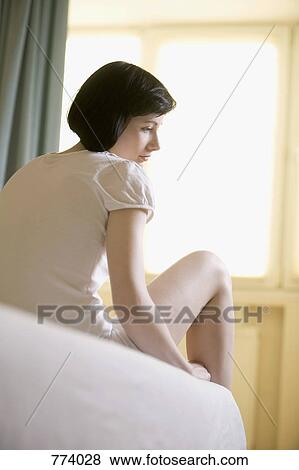 A teenage girl sitting on a bed View Large Photo Image Stock Photo - A teenage girl sitting on a bed. Fotosearch