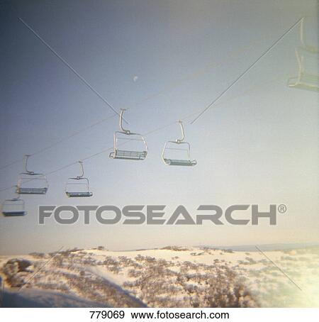 A ski lift above snow-capped mountains View Large Photo Image Stock Photo - A ski lift above snow-capped mountains. Fotosearch