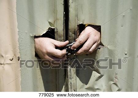 Hands unlocking a chained metal door View Large Photo Image Stock Photography - Hands unlocking a chained metal door. Fotosearch