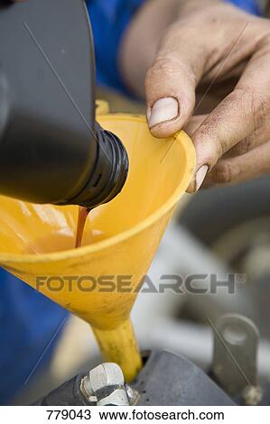Stock Image - Pouring liquid through a funnel. Fotosearch