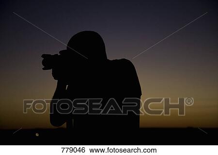 Stock Photograph - Silhouette of a photographer in front of a sunset. Fotosearch