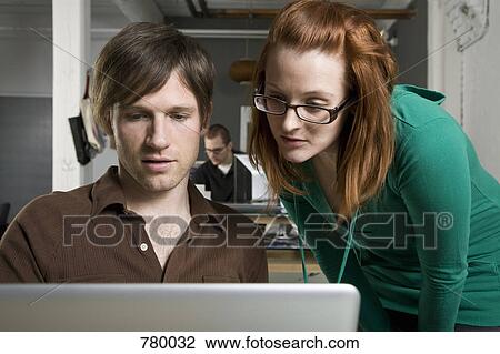 A businessman and businesswoman looking at a laptop View Large Photo Image Stock Image - A businessman and businesswoman looking at a laptop. Fotosearch