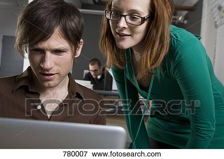 A businessman and businesswoman looking at a laptop View Large Photo Image Stock Photo - A businessman and businesswoman looking at a laptop. Fotosearch