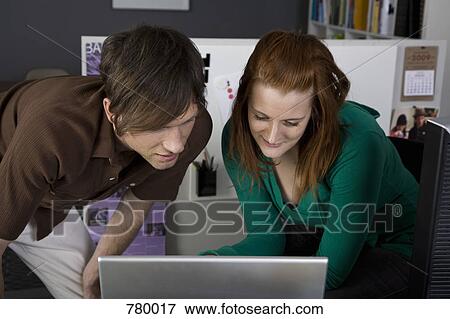 Stock Photo - A businessman and businesswoman looking at a laptop. Fotosearch