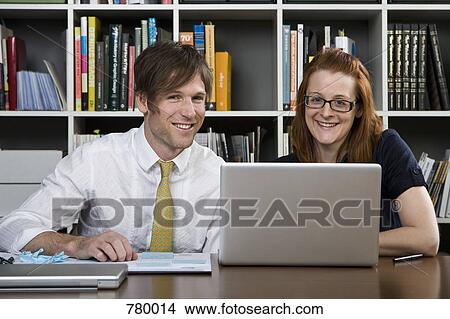 A businessman and businesswoman working with a laptop View Large Photo Image Picture - A businessman and businesswoman working with a laptop. Fotosearch