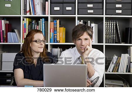 Stock Photo - A businesswoman and businessman working with a laptop. Fotosearch