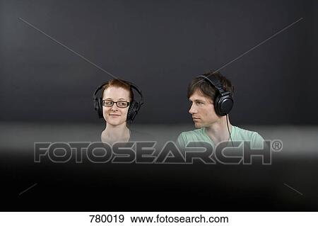 A man and a woman with headphones on View Large Photo Image Stock Photo - A man and a woman with headphones on. Fotosearch