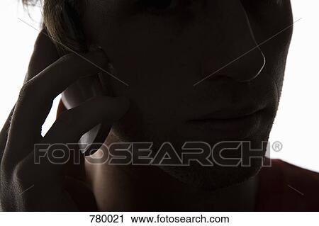 Stock Image - A man on a mobile phone, back lit. Fotosearch