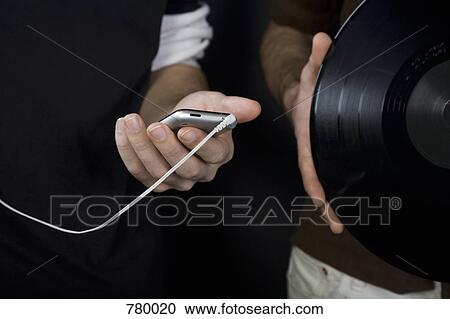 Stock Image - One man holding a MP3 player and another man holding a vinyl record. Fotosearch