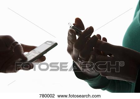 Stock Image - The hands of two people using mobile phones. Fotosearch