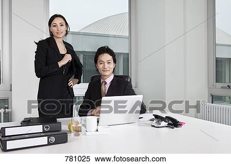 Stock Photography - A businessman and a businesswoman looking at a laptop. Fotosearch