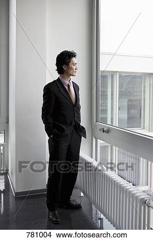 Picture - A businessman looking through a window. Fotosearch