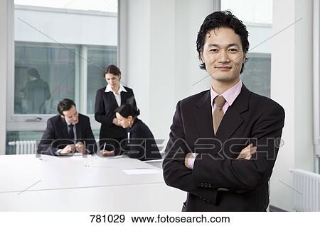Portrait of a businessman in a board room with out of focus business people in background View Large Photo Image Stock Photo - Portrait of a businessman in a board room with out of focus business people in background. Fotosearch