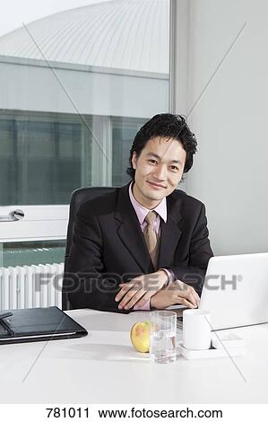 Portrait of a businessman sitting at his office desk View Large Photo Image Stock Image - Portrait of a businessman sitting at his office desk. Fotosearch