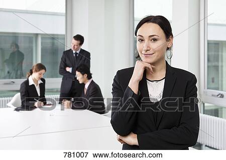 Portrait of a businesswoman in a board room with out of focus business people in background View Large Photo Image Stock Photo - Portrait of a businesswoman in a board room with out of focus business people in background. Fotosearch