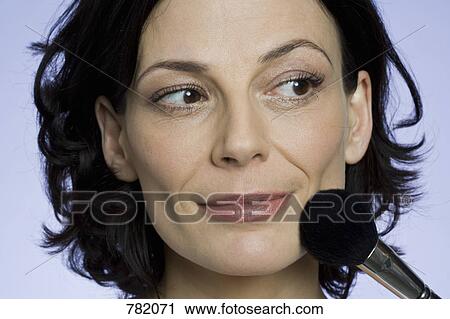 Stock Image - A woman applying face powder. Fotosearch