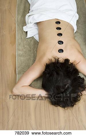 Stock Photo - A woman having hot stone therapy treatment. Fotosearch
