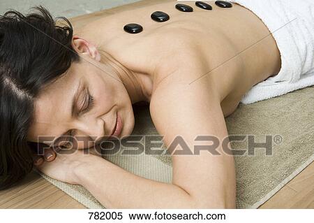 Stock Photography - A woman having hot stone therapy treatment. Fotosearch
