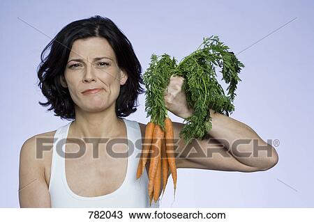 A woman holding a bunch of carrots View Large Photo Image Stock Image - A woman holding a bunch of carrots. Fotosearch
