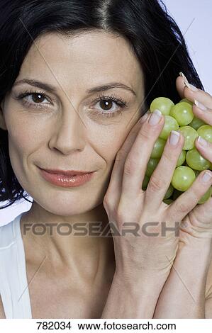 Picture - A woman holding a bunch of grapes. Fotosearch
