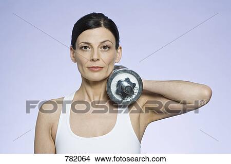 Picture - A woman holding a dumbbell. Fotosearch