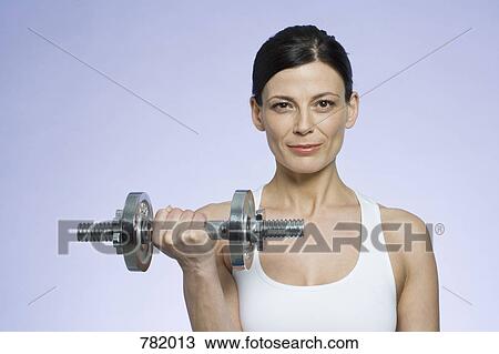 A woman holding a dumbbell View Large Photo Image Stock Image - A woman holding a dumbbell. Fotosearch