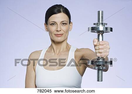 Stock Photography - A woman holding a dumbbell. Fotosearch