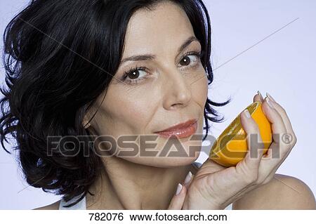 A woman holding half an orange View Large Photo Image Stock Photograph - A woman holding half an orange. Fotosearch