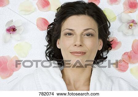 Picture - A woman lying down with flower petals scattered around her. Fotosearch