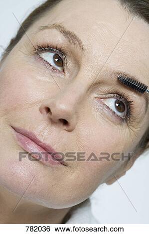 A woman using a make-up brush on her eyebrows View Large Photo Image Stock Photograph - A woman using a make-up brush on her eyebrows. Fotosearch