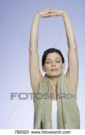 Stock Image - A woman with a towel around her neck stretching. Fotosearch