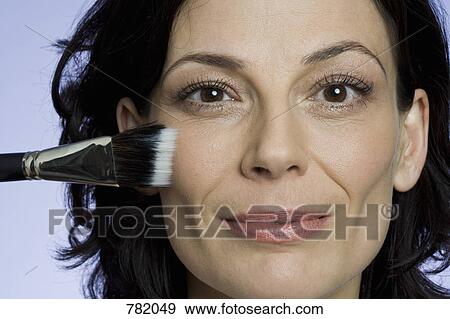 Headshot of a woman applying blusher View Large Photo Image Stock Photo - Headshot of a woman applying blusher. Fotosearch