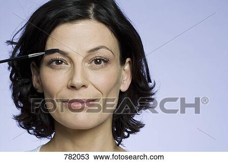 Headshot of a woman applying makeup View Large Photo Image Stock Image - Headshot of a woman applying makeup. Fotosearch